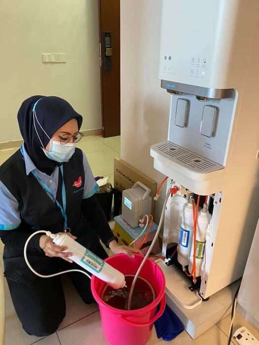 Coway service professional maintaining a water purifier